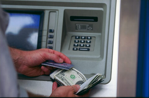 man at bank-automat with credit card and dollars